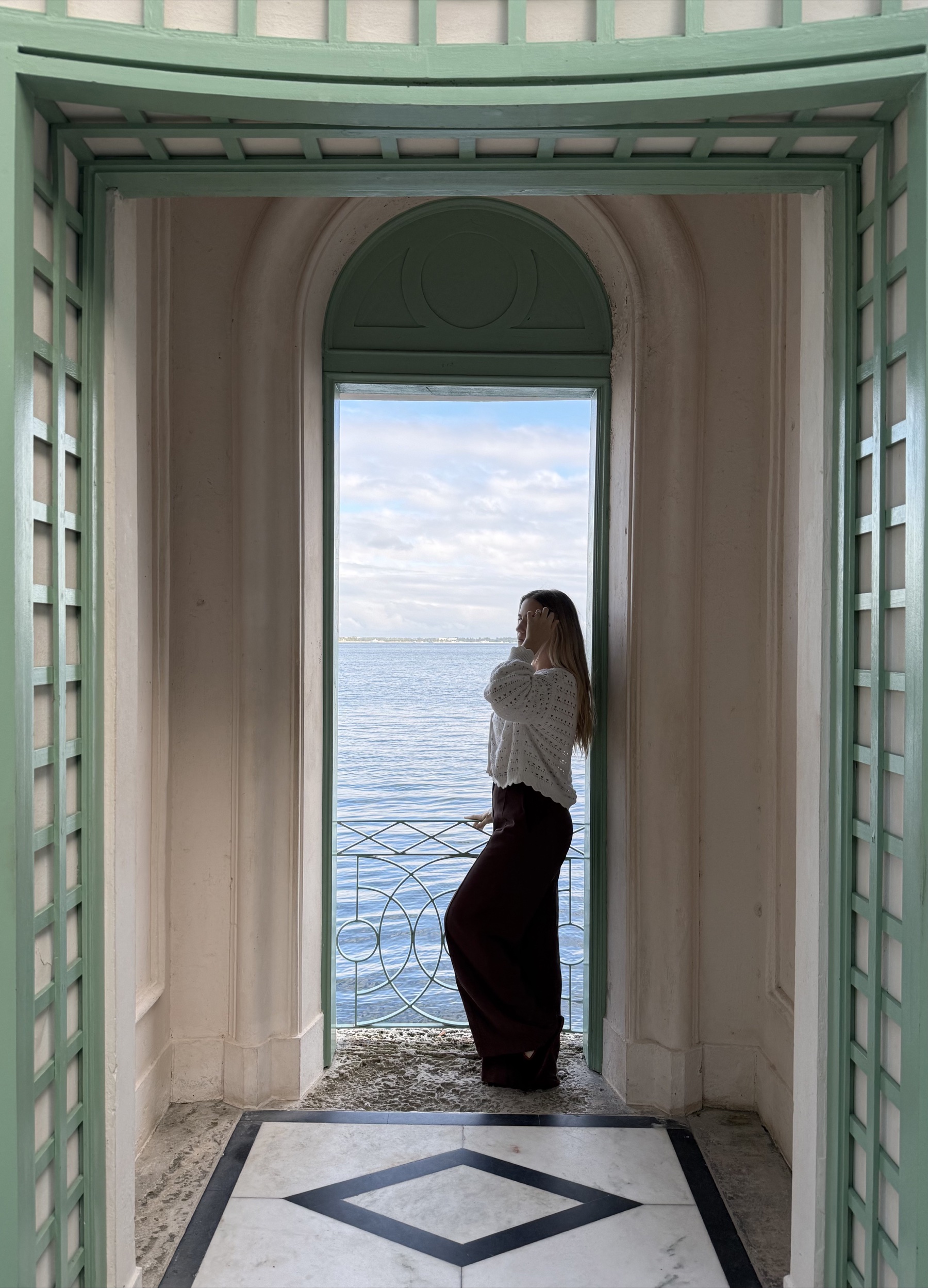 A woman standing in an arched doorway overlooking the water